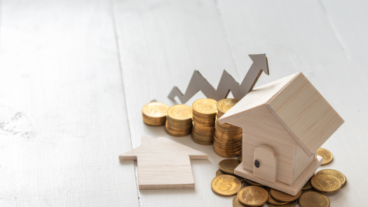Ein kleines Holzhaus auf einem Haufen Goldmünzen neben einer ansteigenden Münzkurve mit Pfeil – Symbolisiert den steuerlichen Gewinn aus dem Verkauf einer Gewerbeimmobilie und die Einhaltung der Spekulationsfrist.